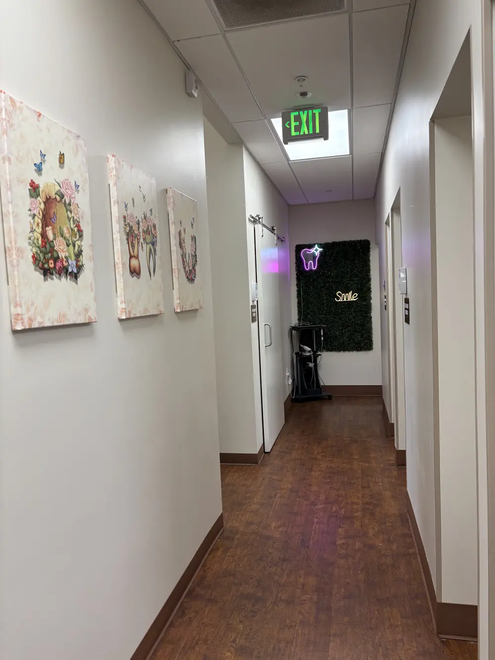Hallway leading to the Smile greenery wall with a neon tooth sign at Valley Dental Turlock