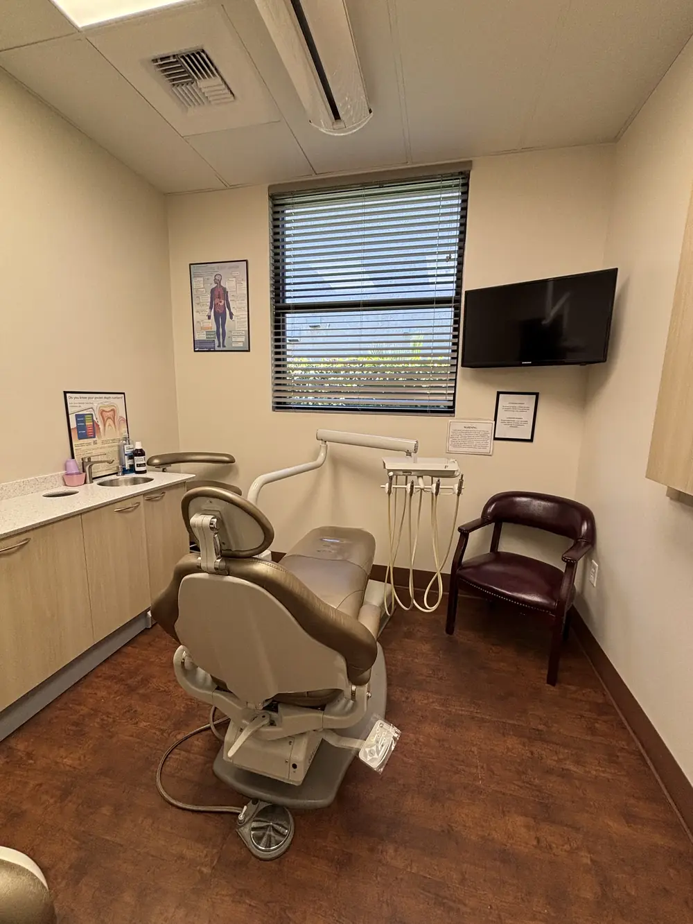 A treatment room with a modern dental chair and wall-mounted monitor at Valley Dental Turlock